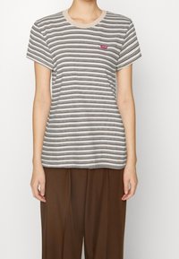 Striped short-sleeve t-shirt in beige, gray, and black. Features a crew neckline and small red Levi's logo on the chest. Soft cotton material.