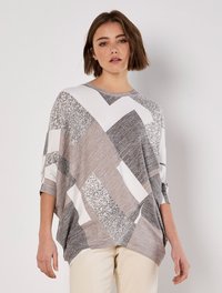 Leichtes Oberteil in Grautönen und Weiß, mit einem geometrischen Patchwork-Design und glänzenden Akzenten. Lockere Passform und Dreiviertelärmel.