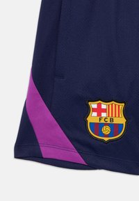 Mørkeblå sportshorts med lilla sidelås og Barcelona fotballklubbmerke på underbenet.