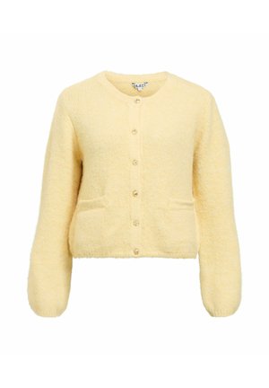 Żółty puszysty kardigan z okrągłym dekoltem, długimi rękawami, przednimi kieszeniami i sześcioma okrągłymi guzikami na środku. Miękka tekstura na całej powierzchni.
