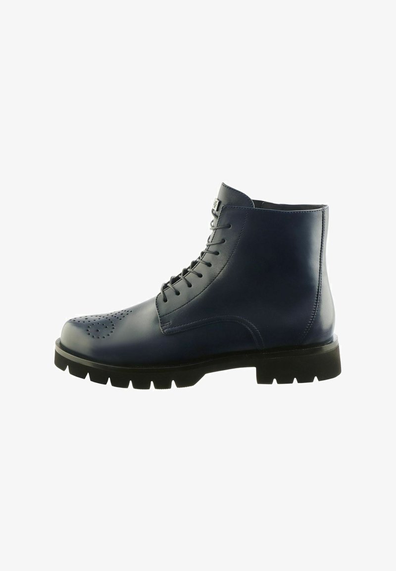 Stivale alla caviglia in pelle blu navy con perforazioni brogue, suola in gomma nera con battistrada, e chiusura con lacci.