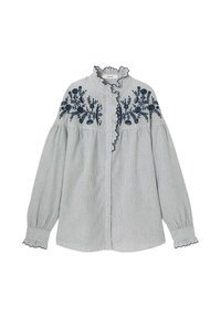 Blouse rayée en coton gris clair et blanc, avec broderie florale bleu marine, col volanté et manches froncées avec des bords en forme de coquille.