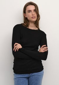 Zwart langslievend shirt van lichtgewicht stof, met een ronde halslijn en een getailleerd ontwerp, gecombineerd met een blauwe spijkerbroek.