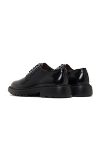 Chaussures en cuir noir avec une finition brillante, un design profil bas, un système de laçage et une semelle en caoutchouc striée pour l'adhérence.