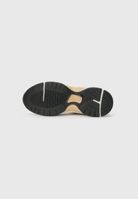 Suela exterior de goma negra con un patrón de agarre texturizado y ranuras laterales. Parte superior en material marrón con un acabado suave.
