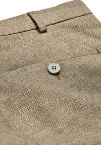 Beige Leinenhosen mit strukturierter Oberfläche, ausgestattet mit einem einzelnen grauen Holzknopf und einer Gesäßtasche. Einfaches und funktionales Design.