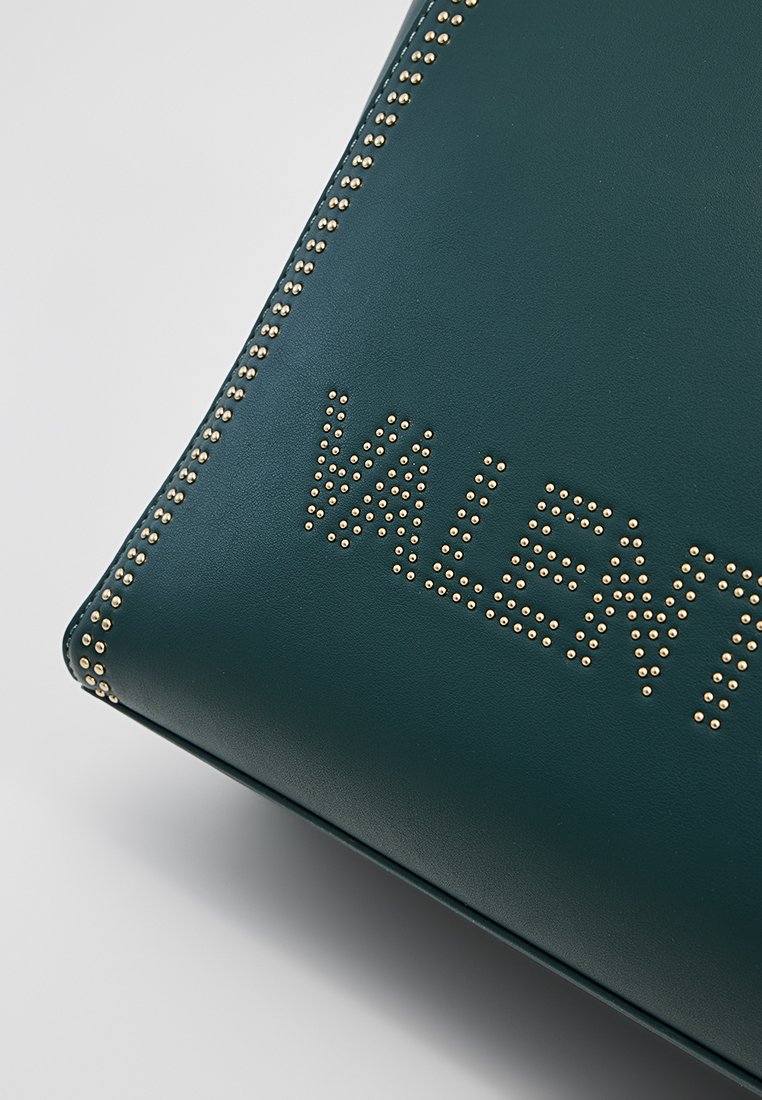 Grüne Leder-Handtasche mit goldenen Nietenverzierungen und eingeprägtem "VALENT"-Text. Glatte Textur, rechteckige Form und saubere Kanten.