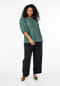 Teal textured top featuring oversized puff sleeves, paired with black wide-leg trousers and olive green pointed flats.