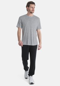 Raidallinen puuvillainen T-paita musta-valkoisena, yhdistettynä mustiin housuihin. Mallilla on päällään valkoiset urheilukengät. Rentoon, väljästi istuvaan muotoiluun.