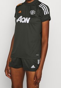 Czarnoszary zestaw koszulki i spodenek Manchester United, z białymi i pomarańczowymi akcentami, krótkimi rękawami i oddychającym materiałem.