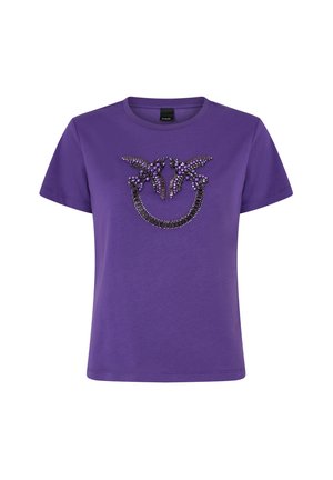 Ljubičasta pamučna majica s ukrasnim uzorkom crnih i ljubičastih ukrasa u stiliziranom dizajnu sprijeda. Kratki rukavi.