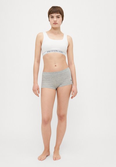 Vit bralette med logoband, parat med ljusgrå stretchiga shorts. Minimalistisk design, mjukt tyg och avslappnad passform.
