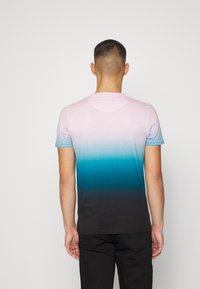 Camiseta de degradado con colores que van desde rosa claro hasta verde azulado, terminando en negro. Mangas cortas y diseño de cuello redondo.