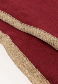 Bordowy materiał z teksturowaną, złotą metaliczną bordiurą. Miękki, gruby materiał z zaokrąglonymi krawędziami i gładką wewnętrzną powierzchnią.