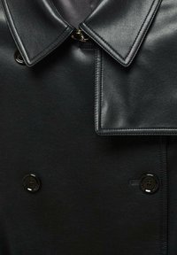 Czarny płaszcz typu trencz z imitacji skóry, z szerokim kołnierzem, dwurzędowymi guzikami i misternymi przeszyciami. Gładka tekstura.