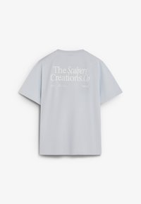 Camiseta de manga corta de color gris claro con texto blanco que dice "The Scalpers Creations.Co" en la parte superior de la espalda.