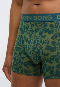 Πράσινα αντρικά εσώρουχα boxer με λουλουδάτο σχέδιο σε σκούρο τιρκουάζ. Διαθέτουν μαλακή μέση με την ετικέτα "BJÖRN BORG" και λείο, ελαστικό ύφασμα.