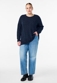 Tume sinine pika varrukaga sviiter tekstureeritud kudumisega. Kombineeritud helesiniste laiade pükstega ja mustade tursketega saappastega, millel on küljetasku.