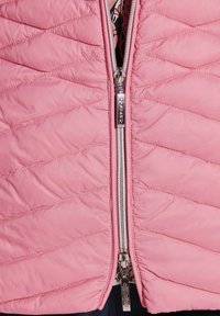 Rosa gesteppte Jacke mit einem Frontreißverschluss und silberner Hardware. Der Stoff hat eine glatte Textur und ein diagonales Steppmuster.