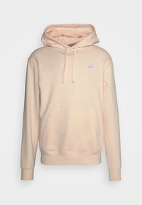 Persikofärgad hoodie gjord av mjukt, lätt tyg, med en framficka, justerbar dragsko för huvan och en liten Nike-logotyp på bröstet.