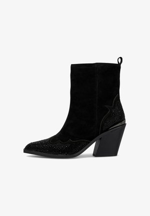 Stivale alla caviglia in suede nero con punta affusolata, design scallop decorativo e impreziosito con gemme nere sulla punta e sul tallone.