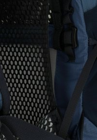 Interno dello zaino caratterizzato da rete nera traspirante, accenti in tessuto blu navy, spallacci regolabili e fibbia sicura. Superfici texturizzate per il comfort.