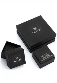 Black packaging boxes of various sizes, made of recycled paper, featuring a white logo "Kuzzoi" and eco-label on one box.