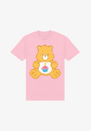 Roze t-shirt met een cartoonbeer met een oranje lichaam en een cupcakeontwerp op zijn buik, gedetailleerd met een kaarsje en kleurrijke accenten.
