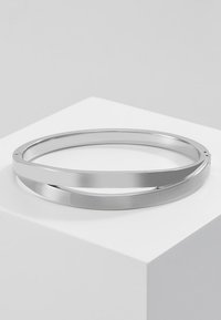 Brățară din argint sub formă de bangle, având două benzi împletite, una lustruită și reflectorizantă, iar cealaltă periată pentru textură. Formă rotundă, margini netede.