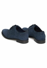 Granatowe zamszowe buty z okrągłymi noskami, płaskimi sznurowadłami i niskim czarnym gumowym obcasem. Minimalistyczny design o gładkiej fakturze i bez widocznych wzorów.