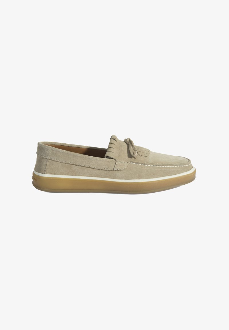 Suède instappers in lichtbeige met een ronde neus, decoratieve kwastjes en een transparante gum zool. Stiksels langs de rand.