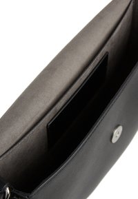 Czarna torebka o teksturowanej powierzchni z gładką szaro-skalą wewnętrzną, z zamknięciem na srebrny guzik i pojedynczą kieszonką na karty. Wnętrze wyłożone miękkim materiałem.