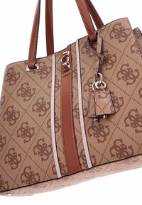 Bruine, gestreepte totebag met twee bruine leren handvatten, zilveren hardware en een decoratief label. Bevat een logo en contrasterende detailstrips.