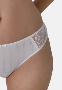 Weiße Spitzenunterhose mit vertikal gestreifter Struktur, zartem Spitzenpaneel an der Seite und kleinen Schleifenakzent auf der Vorderseite.