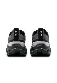 Pantofi sport negri și gri cu un superior din țesătură texturată, amortizare proeminentă a călcâiului și un logo distinct pe spate. Design al tălpii din cauciuc.