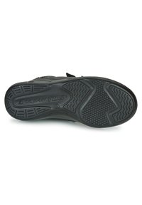 Semelle en caoutchouc noir avec texture antidérapante, présentant un motif ondulé et des indentations circulaires. Marquée "PULSAIR TBS" près du talon.