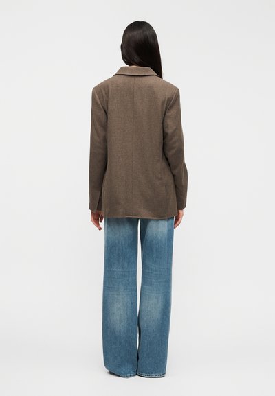 Καφέ σακάκι από μείγμα μαλλιού με γιακά με σχισμή, κλείσιμο με ένα κουμπί και πίσω μέρος με ίσια κοπή, συνδυασμένο με ξεθωριασμένο μπλε τζιν φαρδύ σε ίσια γραμμή.