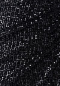 Black fabric covered in shiny sequins, featuring a textured surface with alternating circular patterns and varying shades of black and silver.