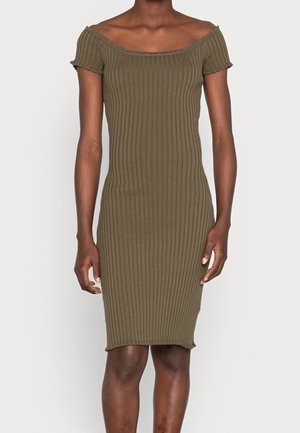 Slim-fit olivengrøn ribstrikket off-shoulder kjole med korte ærmer, der går til over knæet, båret af en stående person.
