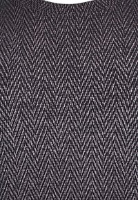 Tkanina v črno-srebrni barvi s vzorcem houndstooth, ki prikazuje chevron vzorec z teksturiranim finišom. Tkanina ustvarja subtilen sijaj.