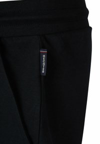 Zwarte sportieve shorts met een ribbelstructuur, voorzien van een opvallend "HECHTER" label aan de zijkant in witte letters met rode accenten.