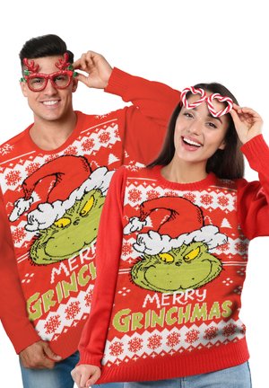 Red knitted Christmas sweaters featuring a Grinch graphic, white snowflake patterns, and text reading "MERRY GRINCHMAS," worn by two people.