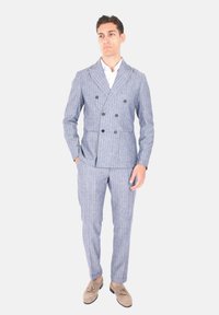 Completo doppiopetto a righe blu chiaro con pantaloni coordinati; vestibilità su misura, tessuto morbido, grandi bottoni e due tasche frontali.