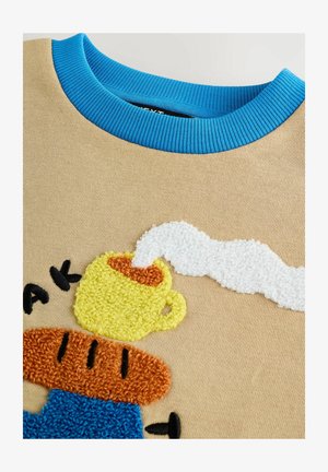 Hanorac bej cu guler ribbed albastru, având broderie texturată și colorată a unei căni galbene și a unei felii de pâine prăjită maronie cu aburi.