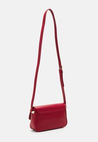 Červená kožená crossbody taška s hladkým povrchem, obdélníkovým tvarem a plochým víkem. Obsahuje dlouhý, nastavitelný popruh a zlaté kovové detaily.