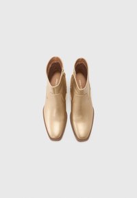 Botine metalice aurii cu un design elegant, vârf ascuțit și fermoare laterale. Textură netedă cu toc mic, îngrămădit.