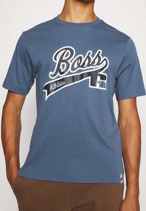 Blaues Baumwoll-T-Shirt mit kurzen Ärmeln, das ein großes weißes "Boss"-Logo und einen diagonalen schwarzen Streifen mit dem Text "Athletic" zeigt.