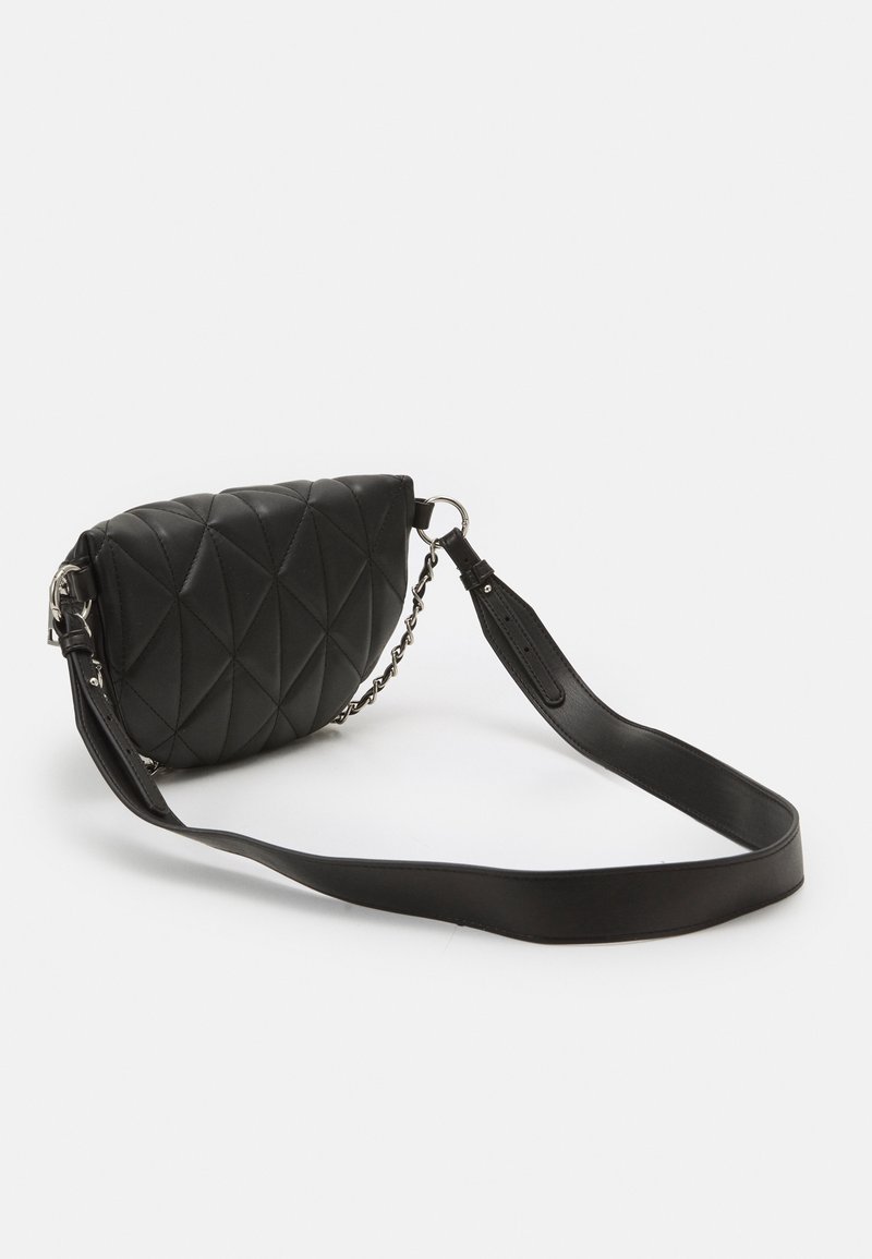 Sac bandoulière en cuir noir matelassé avec une large sangle et un détail chaîne argentée sur un fond clair uni.