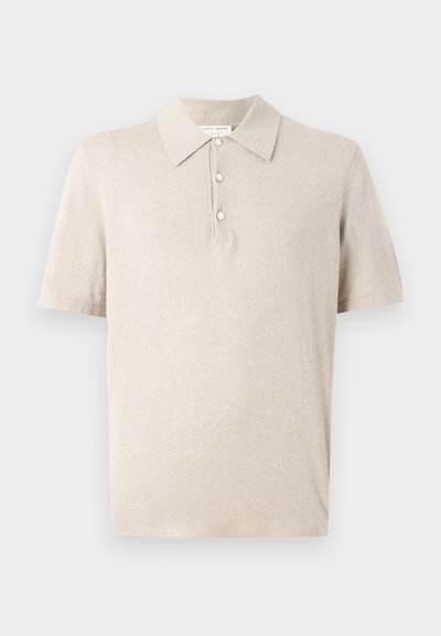 Μπεζ πόλο μπλουζάκι με κοντά μανίκια, τρία κουμπιά και κλασικό γιακά, κατασκευασμένο από μαλακό υφή υφάσματος.