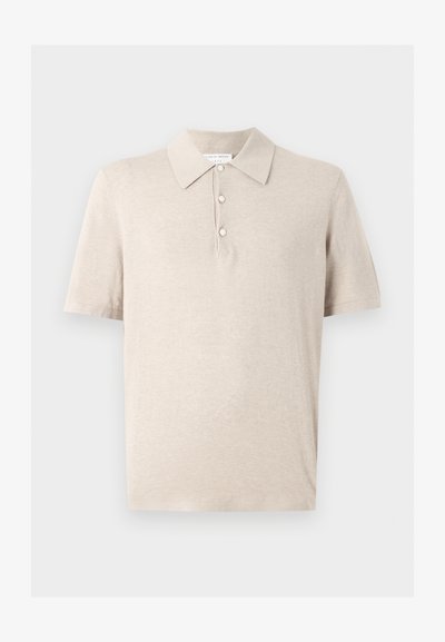 Μπεζ πόλο μπλουζάκι με κοντά μανίκια, τρία κουμπιά και κλασικό γιακά, κατασκευασμένο από μαλακό υφή υφάσματος.